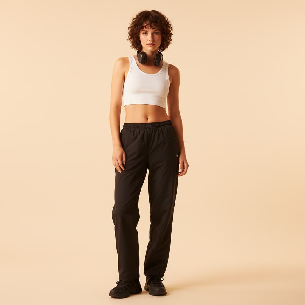 White Cropped Athletic Top Paired With Loose Black Pants And Black Sneakers, Accessorized With A Pair Of Headphones.