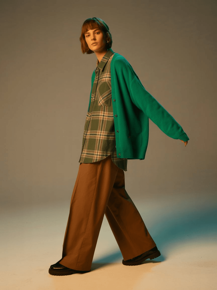 Green Cardigan Over A Plaid Shirt, Paired With Brown Wide-Leg Pants And Black Shoes.