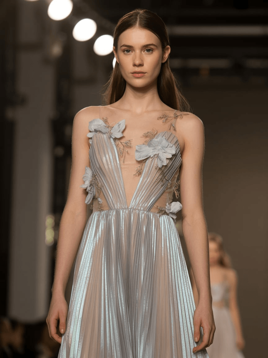 Floor-Length Iridescent Pleated Gown With Floral Appliqués And Sheer Bodice Details.