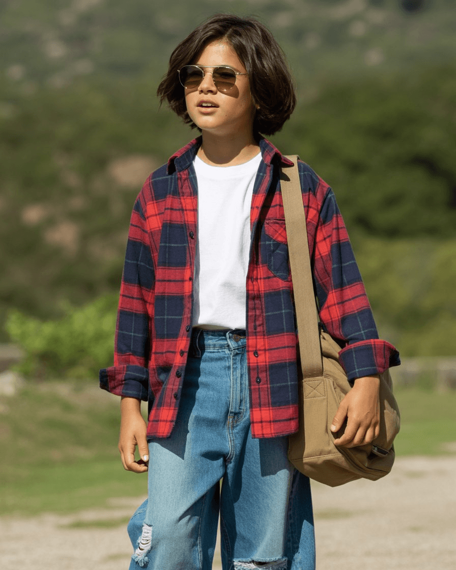 Red And Navy Plaid Overshirt Layered Over A White Tee, Styled With Distressed Wide Denim Pants, Sunglasses, And A Beige Messenger Bag